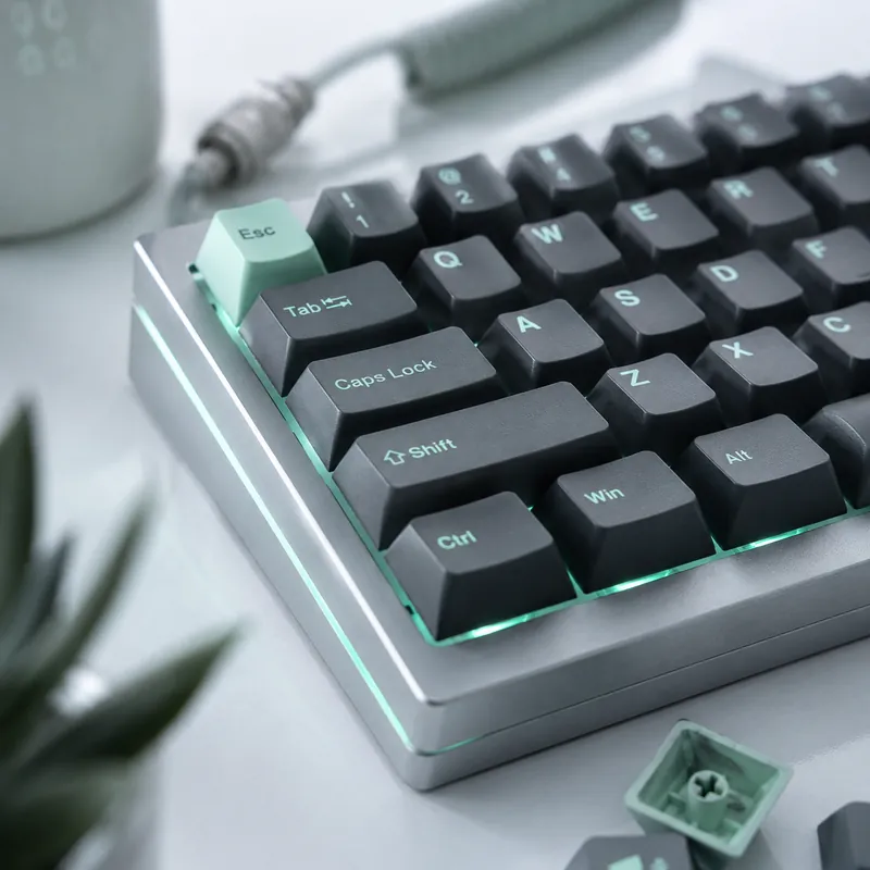 Detalle de un teclado mecánico gris con retroiluminación en tono menta, parte del set de periféricos de la estación Pro.